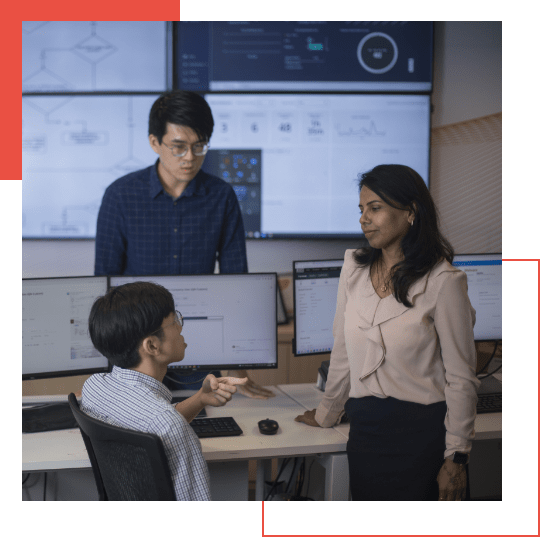  Three colleagues discussing in front of computer monitors displaying various data and charts in a modern office setting, including insights from Google Chronicle and the latest MXDR solutions.