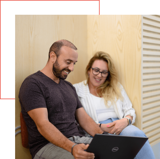  A man and woman sit together, smiling as they explore an MDR platform on a laptop screen in a wooden-paneled room.